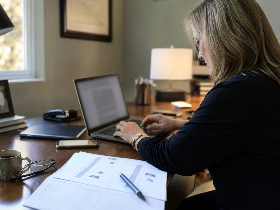 Independent financial advisor at a desk in her office drafting a LinkedIn post from her quarterly market commentary