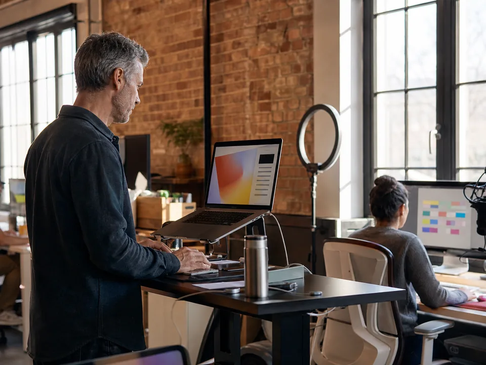Agency founder turning a recorded webinar into social posts on a laptop while a teammate checks the weekly content calendar